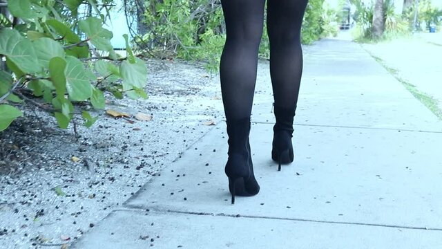 Gen Z girl in black tights walking on sidewalk