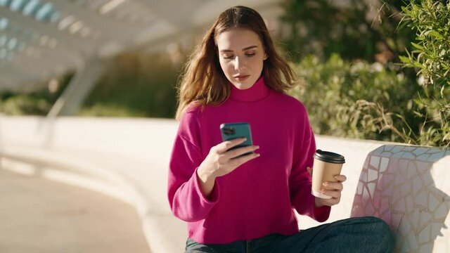 Young blonde woman using smartphone drinking coffee at park