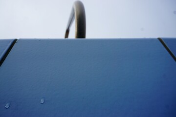 Blaue Schwimmbeckenrandkachel mit zwei Regentropfen und Rundgeländer aus Stahl im Schwimmbad im...