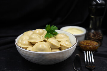 Boiled Russian dumplings in a deep dish. Black background.