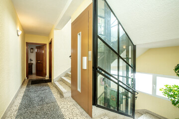 Common areas of a residential building with an elevator shaft covered with glass panels