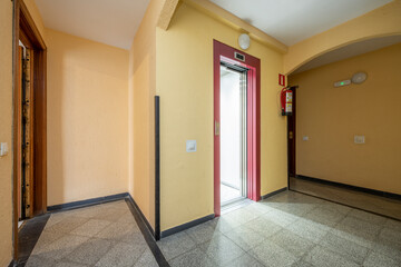 Common areas of a residential building with a red elevator and terrazzo floors