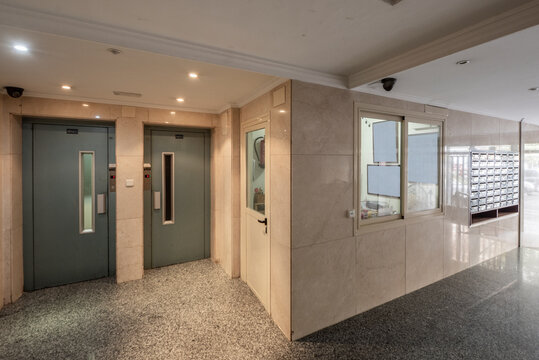 Common areas of a residential building with double elevator with cream marble walls and gray granite floors