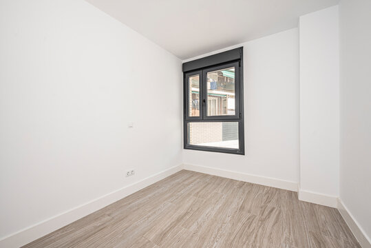Empty room with black aluminum window, white walls and porcelain stoneware floors