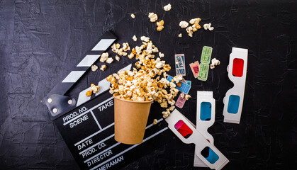 Cinema minimal concept. popcorn, 3d glasses clapper board on black background. Flat lay, top view