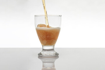 stream of beer falling into a crystal glass is a white background