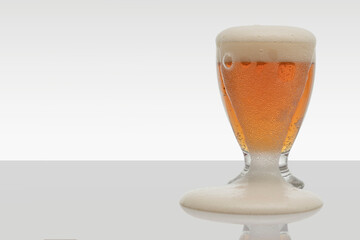 Full beer glass and spilling foam down the side, copy space for text