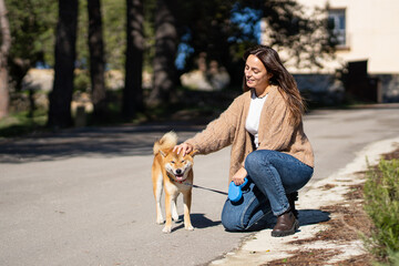 smiling woman petting a shiba inu dog