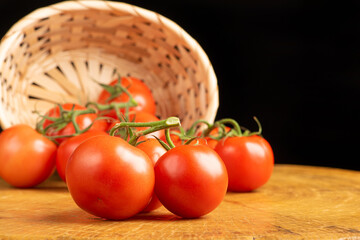 Tomatoes, beautiful tomatoes falling from a straw basket on rustic wood, selective focus.