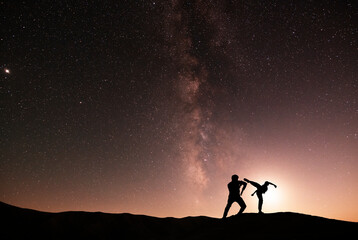 Silhouettes of karate fighters on the background of the starry sky. Beautiful milky way galaxy....