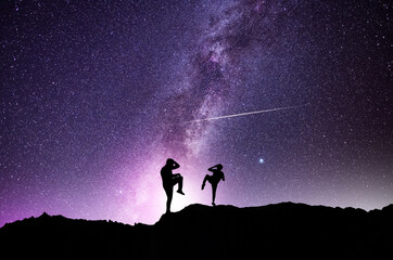 Silhouettes of karate fighters on the background of the starry sky. Beautiful milky way galaxy. Night scenne. © Inga Av