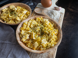 Side view of two plates of Nelga Rice along with various ingredients on a table.