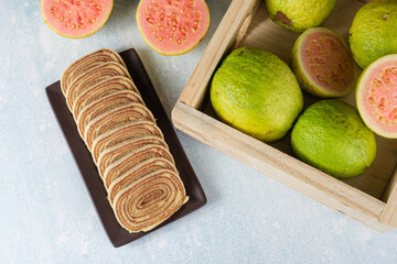Sliced bolo de rolo next to a box with guavas (top view).