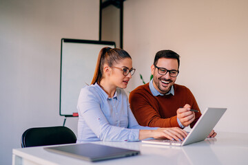 Happy businesspeople working together in the office while using laptop