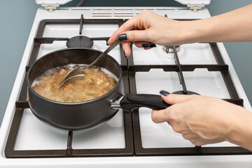 a woman's hand takes a spoonful of pasta out of the pan