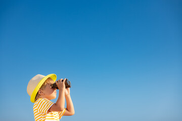 Child looking through binoculars in summer