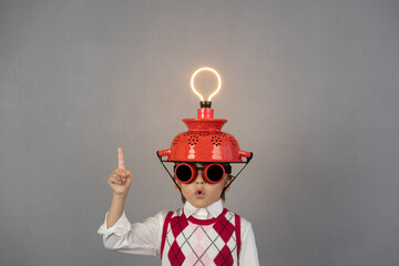 Smart child wearing funny helmet with illuminated lightbulb - obrazy, fototapety, plakaty