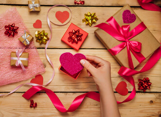 Women's hands hold a paper heart on a wooden background. The concept of Valentine's Day, Mother's Day.