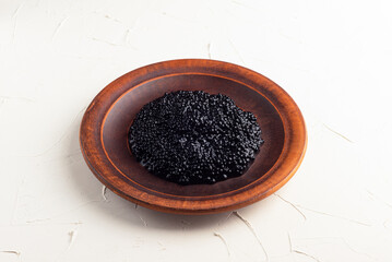 black caviar, fish caviar, in a wooden plate on a white background