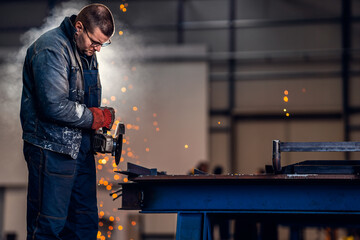 Factory worker cutting metal with grinder.