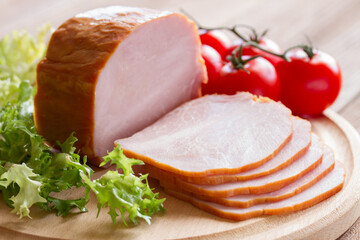 Sliced ham with tomatoes and lettuce on a wooden background