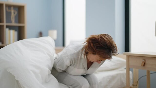 Middle age woman waking up suffering for stomachache at bedroom