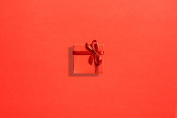 Bright red square gift box on a red paper background. Top view. A passionate gift.