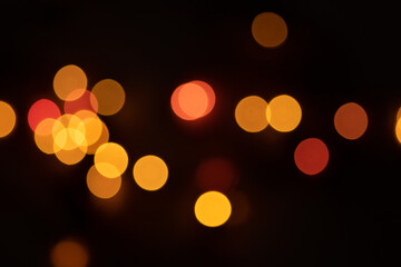 Fototapeta premium Defocused bokeh lights on black background, an abstract naturally blurred backdrop for Valentine's Day or birthday party. Festive light texture. Pink and red garland in blur. Overlay effect for design