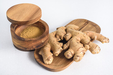 Ginger root and ginger powder in the wooden bowl