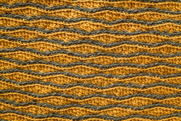 Yellow grey crocheted wave pattern. Knitted texture.