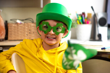 happy schoolboy on st. patrick's day. wearing a green hat, wearing green clover-shaped glasses,...