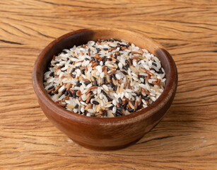 Raw assorted rice in a bowl over wooden table