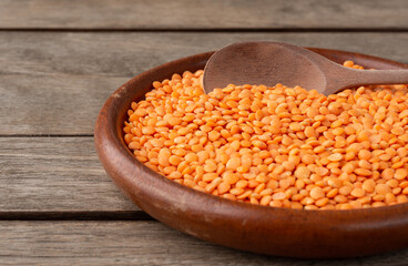 Narrow focus, orange lentil on a plate over wooden table with copy space