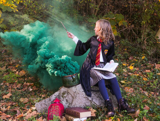  Witch girl with magic wand cosplay wizzard outdoor. Halloween holiday. Girl going green magic....