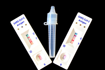 2 covid-19 antigen self-tests positive and buffer bottle on black background. Self test. test at...