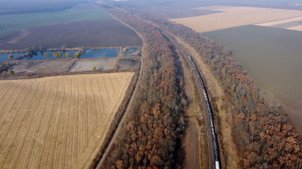 Panoramic View of Moving Freight Train Along Railway Tracks Among Trees Between Agricultural Fields...