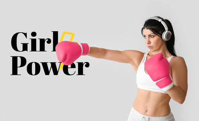 Fototapeta na wymiar Sporty woman in boxing gloves and text GIRL POWER on light background