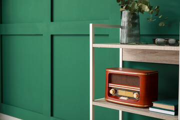 Bookcase with retro radio receiver near green wall