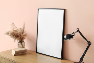 Blank poster on table with lamp near color wall