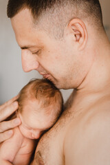 Close-up portrait of father holding sleeping newborn son on his arm. Head of newborn baby on father's chest. Selective focus. Film grain