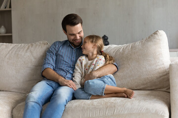 Happy bonding affectionate young father embracing little preteen kid daughter, talking speaking...