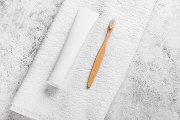 Tube with tooth paste, brush and towel on light background