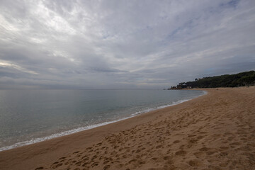Sandy coast and stones under a cloudy sky on the Costa Brava, Spain. Picturesque seascape with a coast.