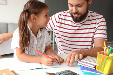 Man helping his little daughter to do lessons at home