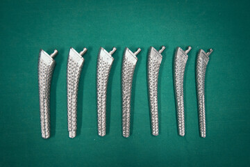 Surgical rasps of different sizes for a transfemoral prosthesis lie on a green surgical drape