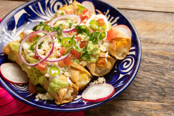Mexican fried potato tacos called flautas with guacamole and cheese