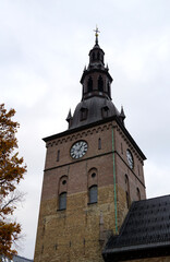 Fototapeta na wymiar A church tower with a clock showing the exact time on a cloudy day