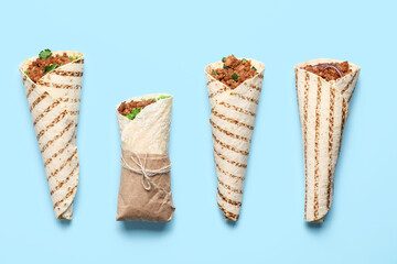 Different tasty burritos on blue background