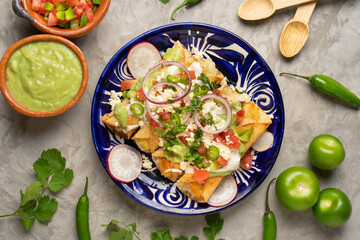 Mexican fried potato tacos called flautas with guacamole and cheese