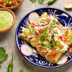 Mexican fried potato tacos called flautas with guacamole and cheese